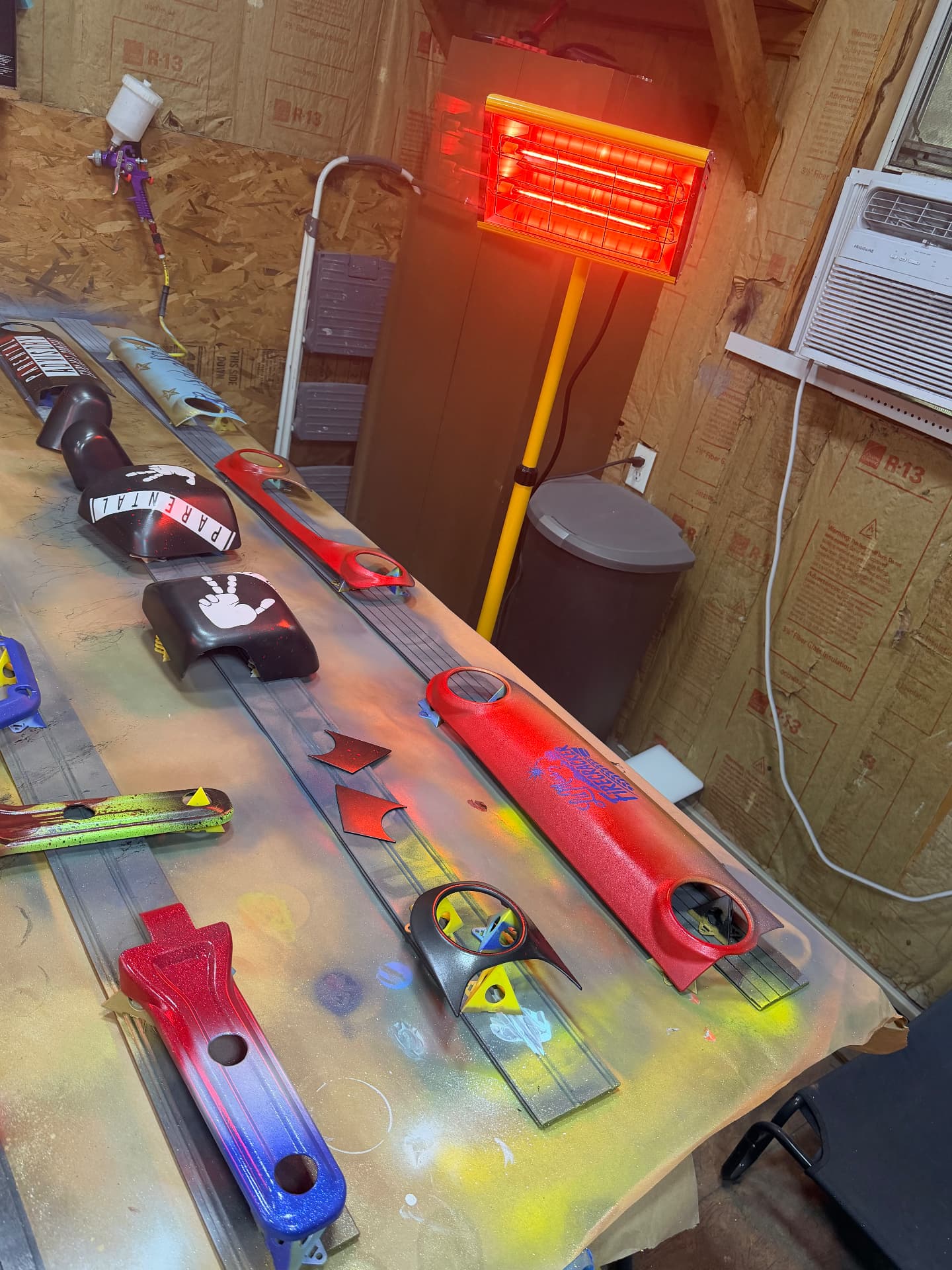 Row of freshly painted custom Jeep trim pieces under the cure lamp